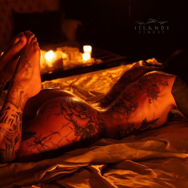 island's finest escort harlow laying on champagne sheets sweat on small of back and round booty glistening in candlelight 650